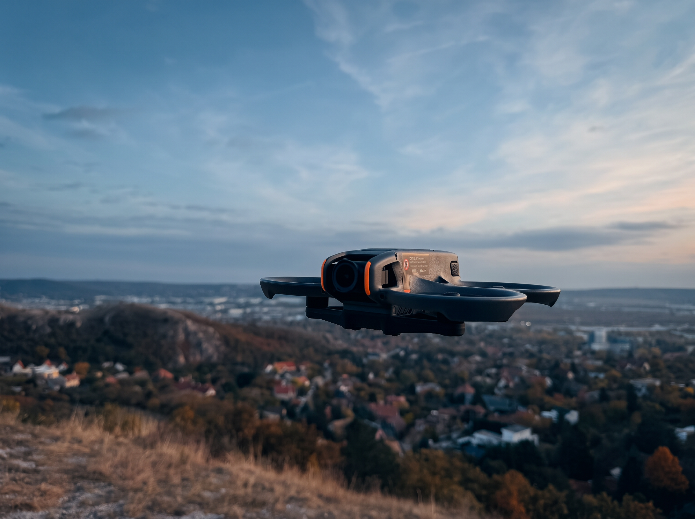 DJI Avata 2 FPV drón repülés közben a város felett, alkonyatkor